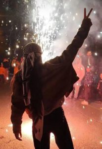 Mujer levantando la mano en señal de victoria, sobre un fondo de manifestación nocturna
