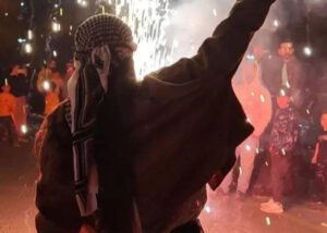 Mujer levantando la mano en señal de victoria, sobre un fondo de manifestación nocturna