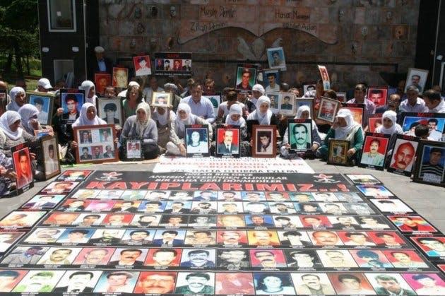 Mujeres con una manta de fotografías de hijos desaparecidos y fallecidos